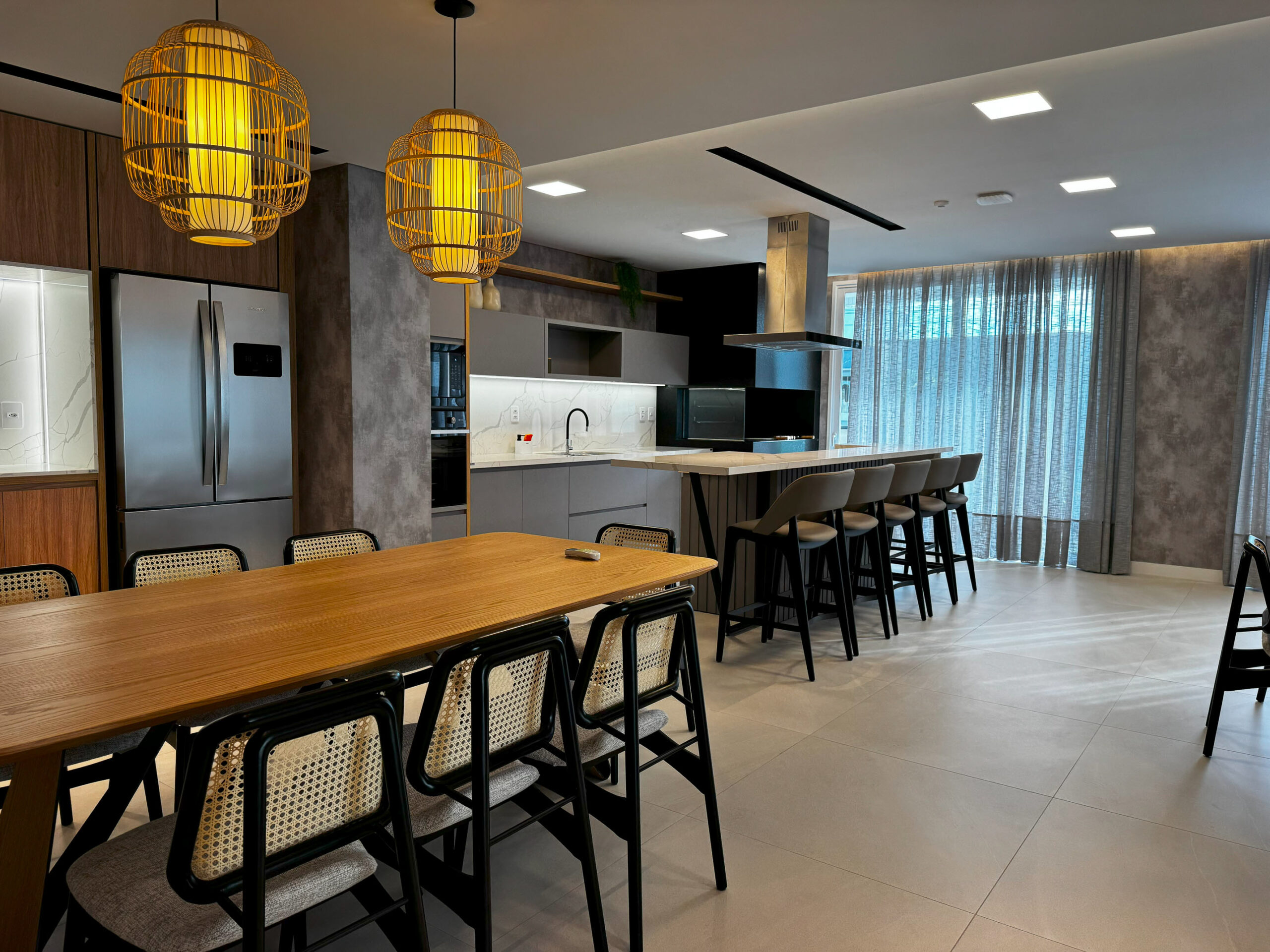 Área social com bancada de madeira e banquetas altas